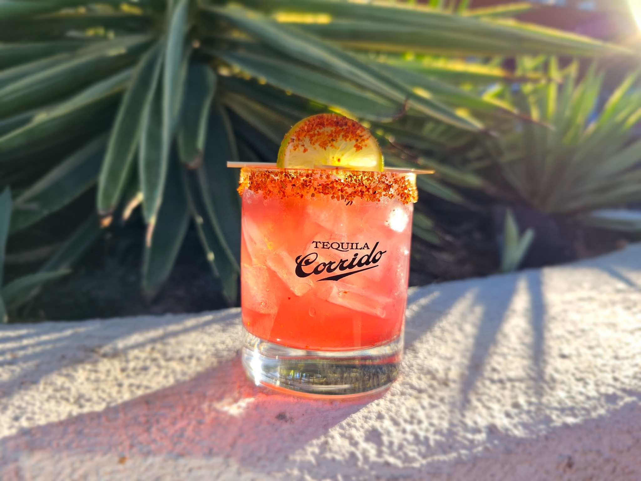 Pink custom tequila cocktail with a spiced rim and lime garnish