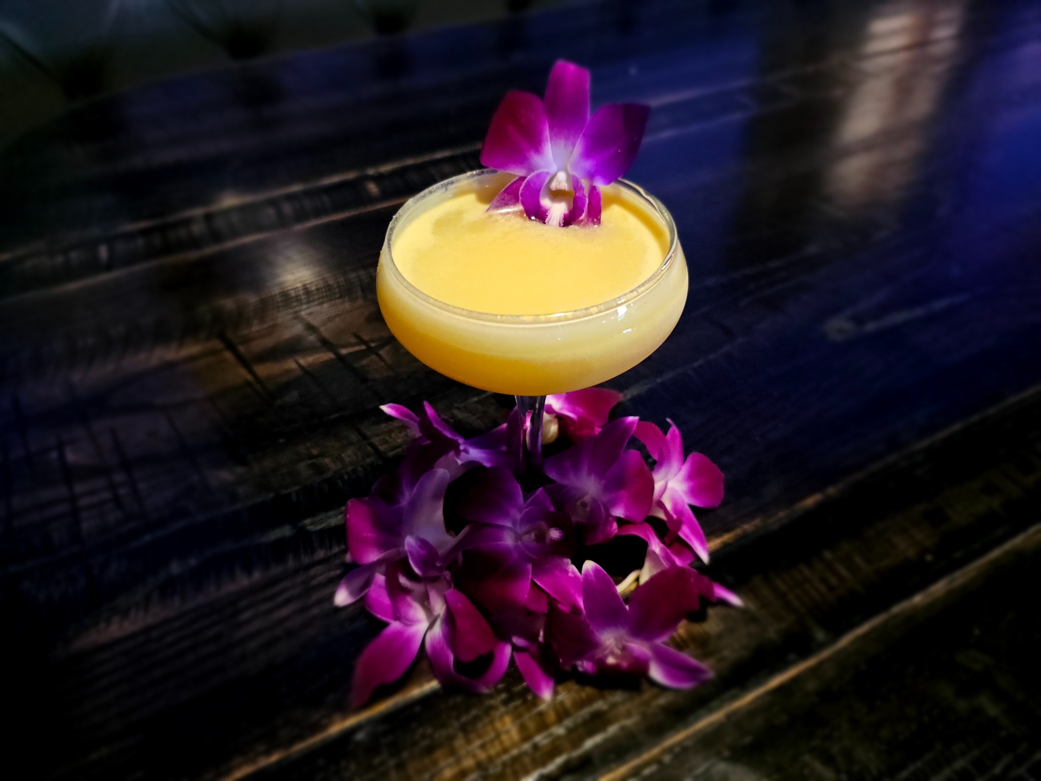 Yellow custom cocktail garnished with purple orchids